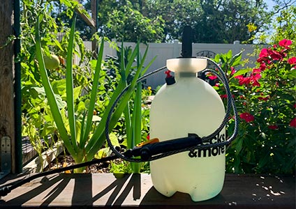 2-gallon sprayer against a thriving garden backdrop